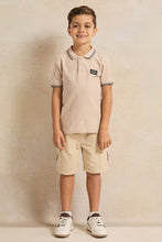 Load image into Gallery viewer, قميص بولو للأولاد باللون البيج مع شعار على الصدر وياقة مائلة